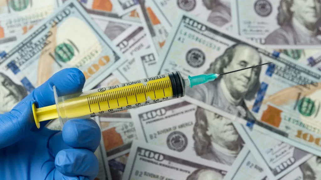 Nurse Hand Holding Syringe on Money Background