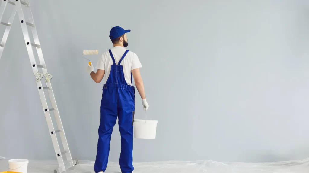 Painter carrying a bucket of paint and looking at the wall, transforming the space with style