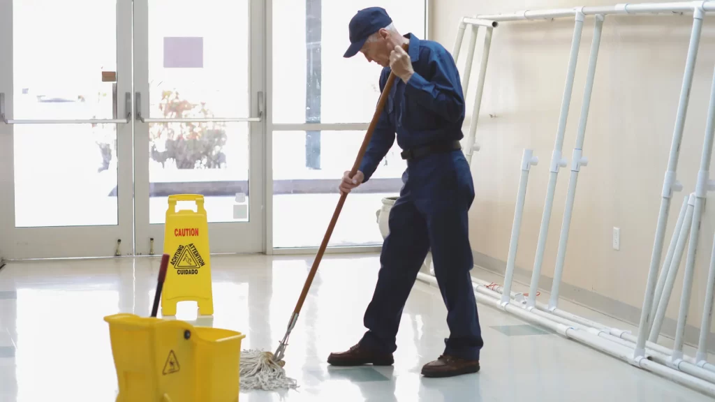 Adult male janitor mopping floor in office building - symbolizing janitor skills and qualifications