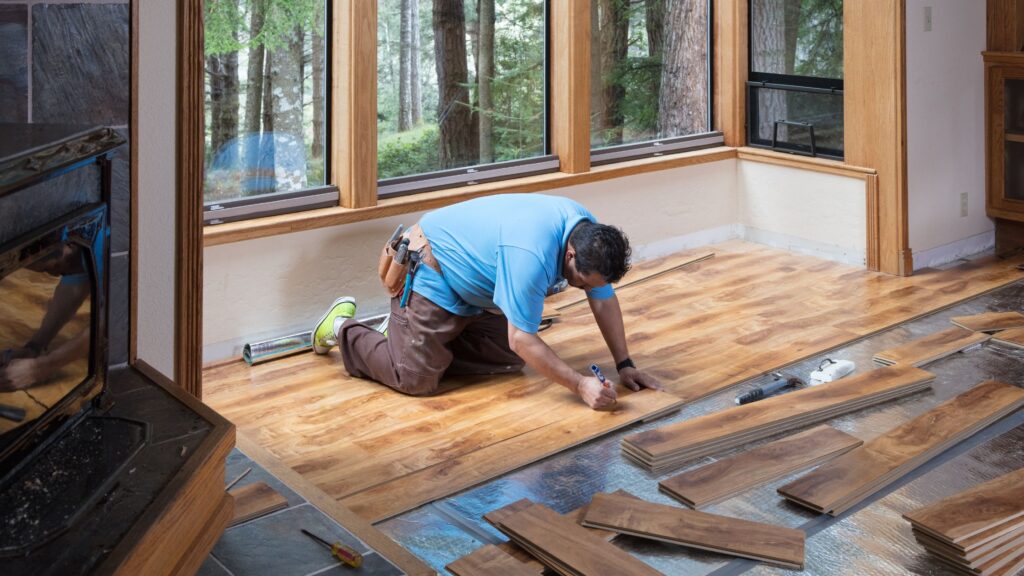 A contractor installs new wooden flooring in a modern home, showcasing the latest trends and types of flooring materials