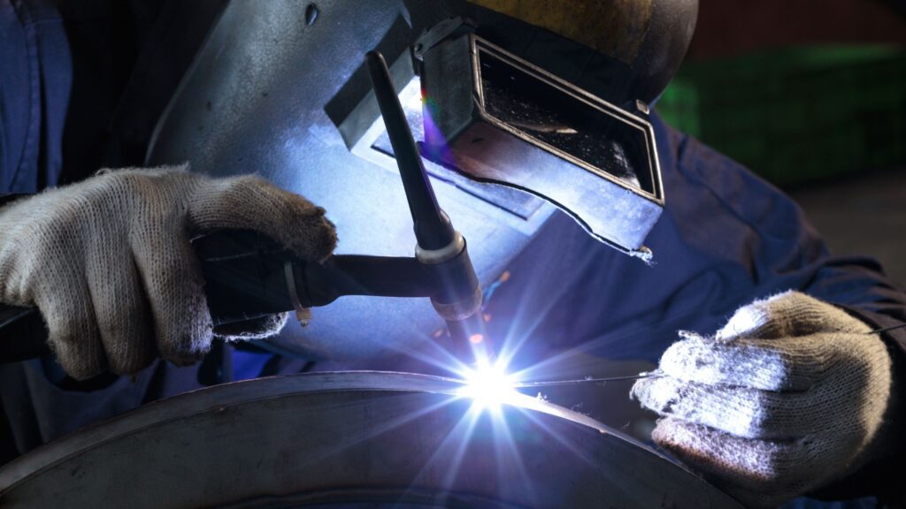 Welder using protective gear while performing welding on metal, showcasing metallurgic creativity with sparks