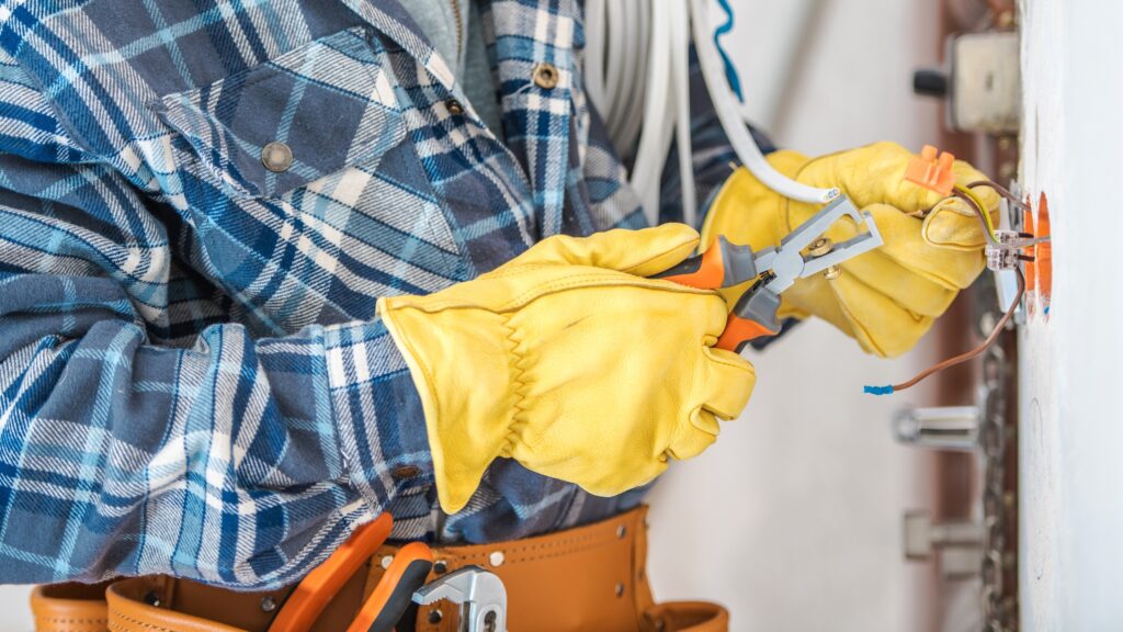 Electrician using pliers to work on electrical wiring, highlighting steps to get an electrician license