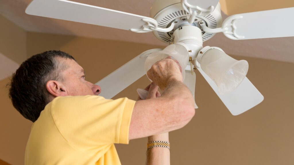 An Electrician Installing a Ceiling Fan, Showing What Impacts the Cost of Ceiling Fan Installation