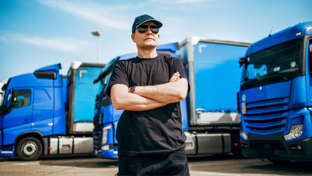 Truck driver standing confidently in front of trucks illustrating how much does a truck driver make in 2024