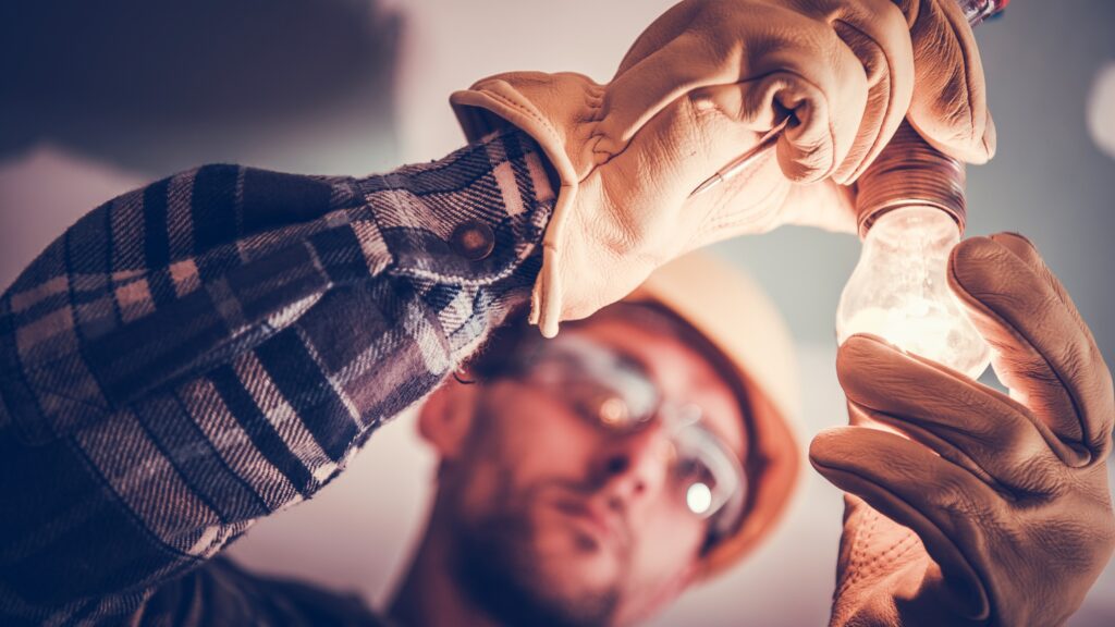 Electrician installing a light bulb, showcasing the importance of finding a reputable electrician