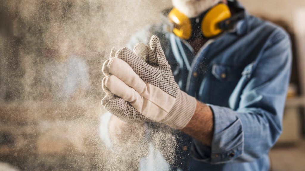 Carpenter wearing protective gloves and earmuffs, highlighting essential safety equipment for carpentry work