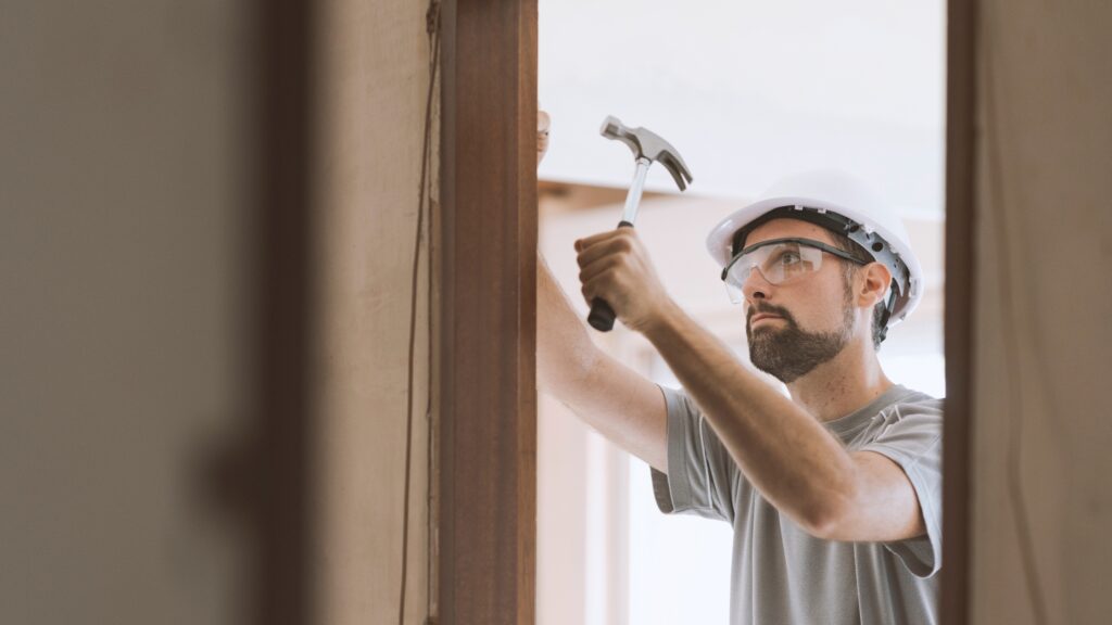 Carpenter using a hammer and wearing safety gear, illustrating essential tools for carpentry work