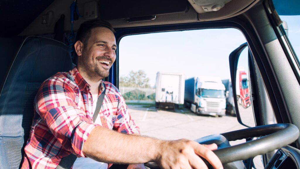 Smiling truck driver behind the wheel demonstrating daily driving limits and how many hours a truck driver can drive