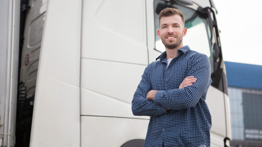 Confident owner-operator truck driver standing by his truck, ready to start a successful trucking business in 2024