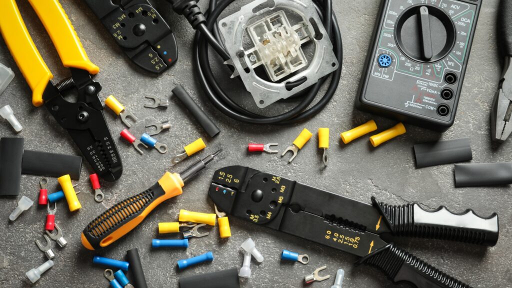 Various tools from an electrician tools list, including wire strippers and a multimeter, essential for any toolbox