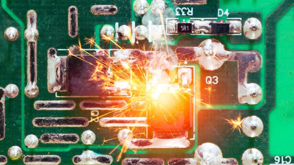 Damaged circuit board sparking due to a power surge, emphasizing the importance of protecting devices from electrical spikes