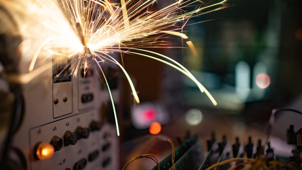 Sparks from an overloaded electrical device, illustrating how power surges are caused by faulty wiring or overloaded circuits