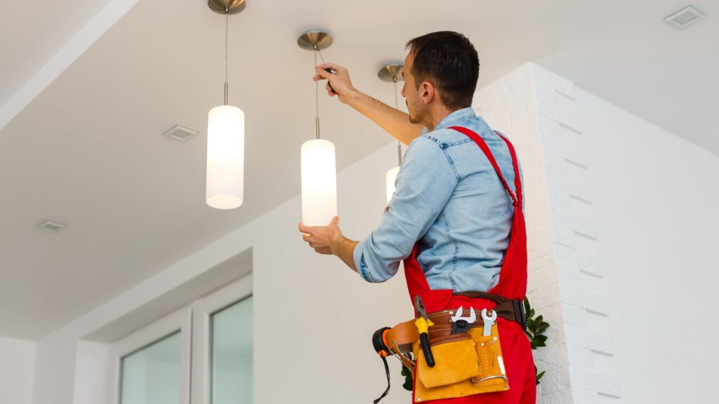 An electrician fixing a ceiling light, highlighting when to call a professional for flickering lights