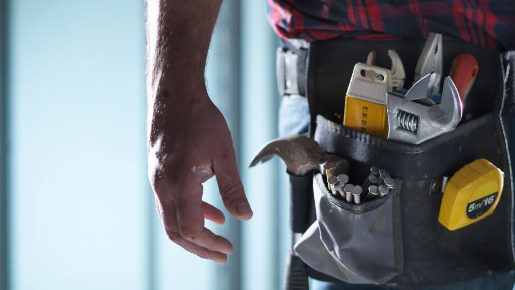 Close-up of a worker's tool belt with nails, hammer, and wrenches, showing the best tool belt for professionals in 2024