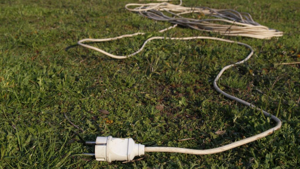 Outdoor extension cord laying on grass, showcasing the importance of choosing the right extension cord for outdoor use