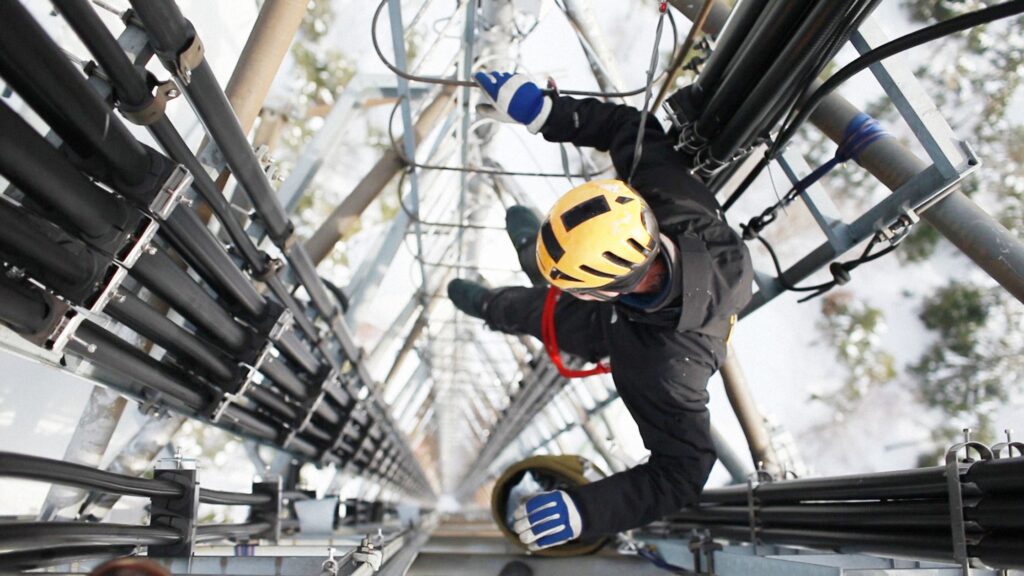 Tradesman wearing winter gear on a high structure, highlighting the importance of winter gear for tradesmen